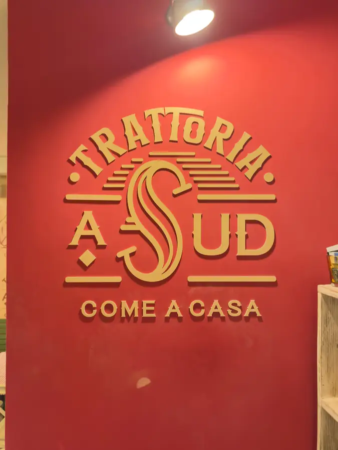 L’insegna Trattoria aSud, come a casa, sul muro rosso
