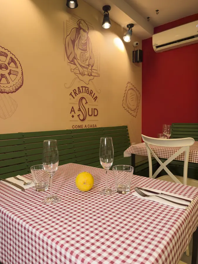 La sala con la carta da parati della nonna, la panca verde e le tovaglie a quadri